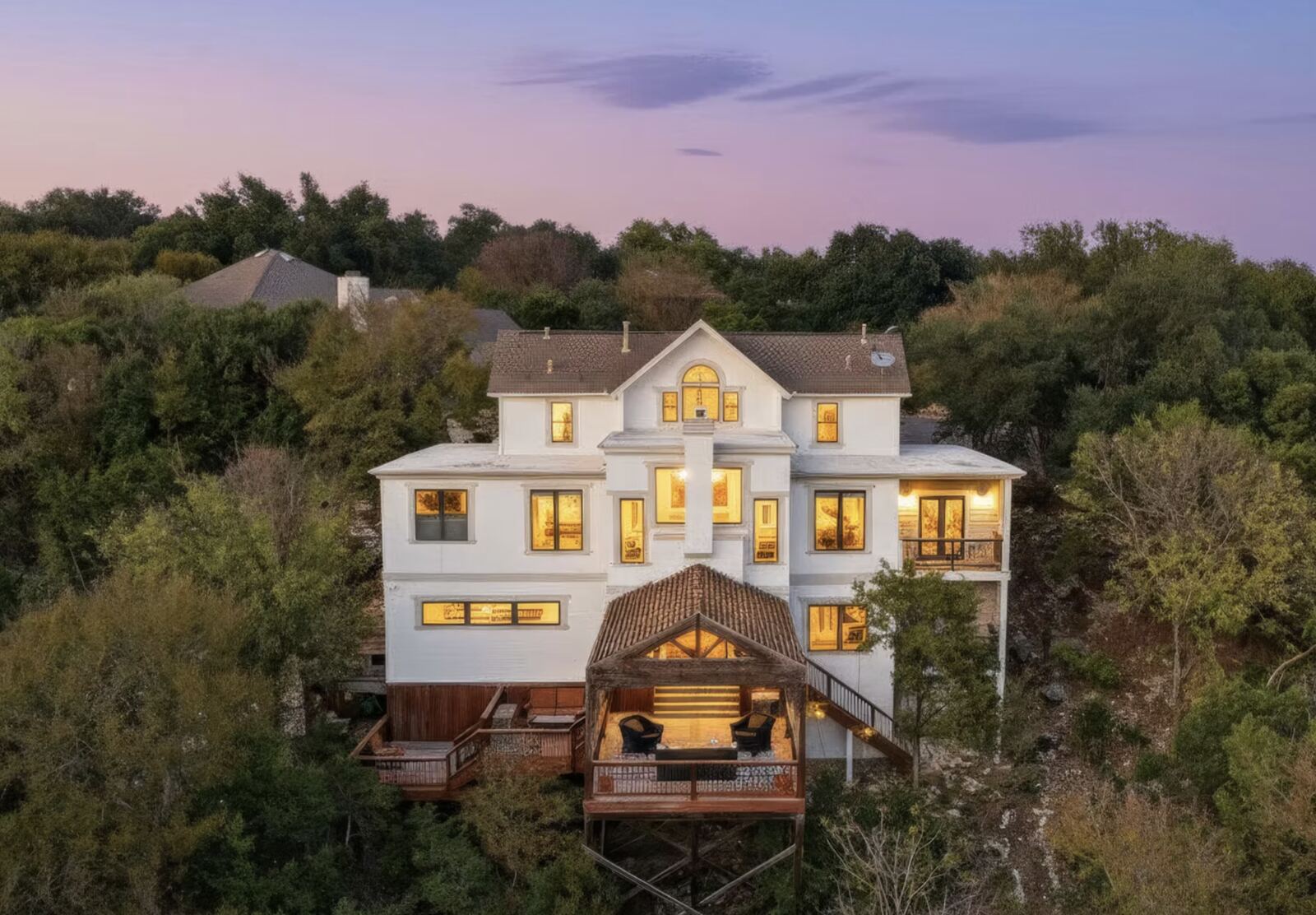 Aerial twilight photo of a three-story home in the trees
