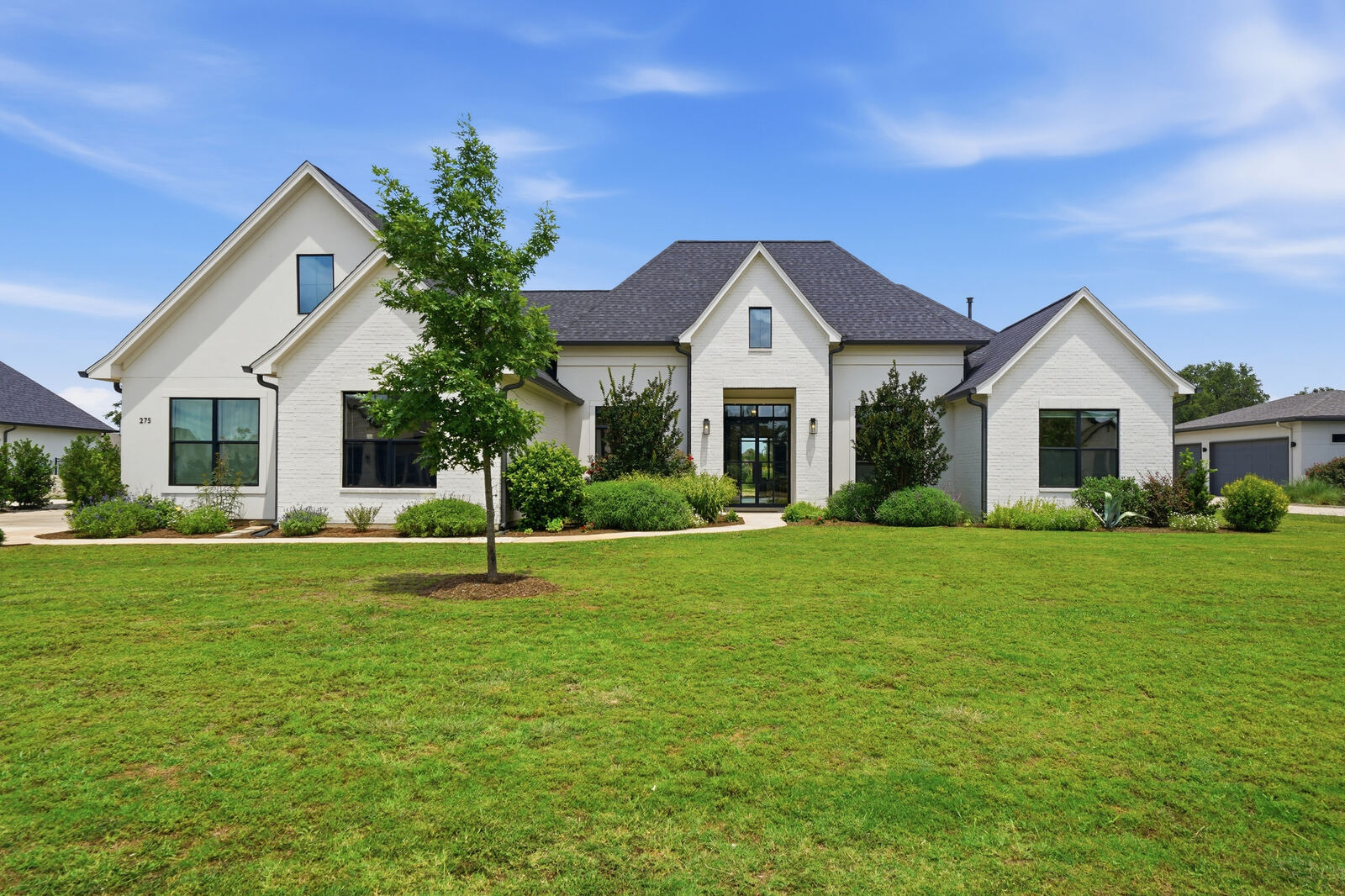 White brick modern farmhouse exterior on a green lawn